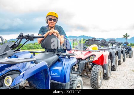Una signora siede sulla bici anteriore di una fila di quad e posa per una foto a Balik Pulau, Penang, Malesia. Foto Stock
