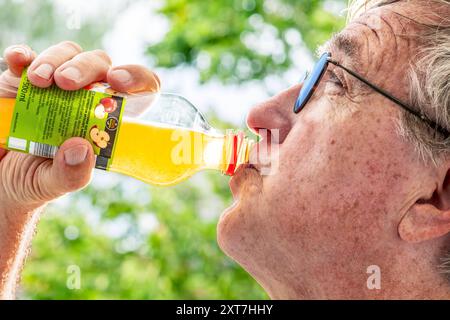 Mann löscht seinen Durst mit Apfelschorle, viel Trinken ist bei der Hitze für Ältere besonders wichtig, München, agosto 2024 Deutschland, München, agosto 2024, ein älterer Mann löscht seinen Durst mit Apfelschorle, bei der Sommerhitze ist Trinken für alte Menschen besonders wichtig, müssen ausreichend Flüssigkeit zu sich nehmen, sonst droht Gefahr der Dehydrierung, Abkühlung an einem Warmen Sommertag, Temperaturen über 30 Grad, aus der Flasche trinken, Senioren, Renthordner, Ü60, Rekze, Rekorditze, Sommerwetter, Hochsommer, Sommer, Bayern, *** l'uomo disseta con spritzer di mele, bevendo molto Foto Stock