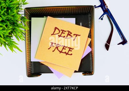 Simbolo concettuale di esenzione dal debito. Copia spazio. Le parole senza debiti scritte sull'adesivo giallo hanno una vista dall'alto Foto Stock