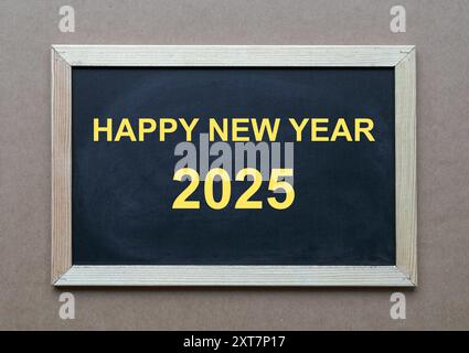 Felice anno nuovo 2025, testo digitato in giallo sulla lavagna. Foto Stock