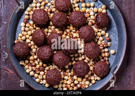 Baci de Alassio, biscotti italiani fatti con impasto di noci ripieno di ganache al cioccolato su uno sfondo di nocciole sgusciate. Foto Stock