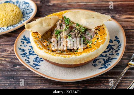 Stinco di agnello con pilaf bulgur e parte superiore ricoperta di impasto della cucina tradizionale turca Foto Stock