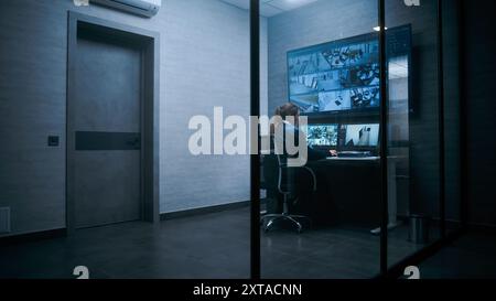 L'operatore di sorveglianza femminile controlla le telecamere di sicurezza nel moderno centro di monitoraggio utilizzando un computer. Riprese video CCTV su più monitor e grande schermo digitale. Foto Stock