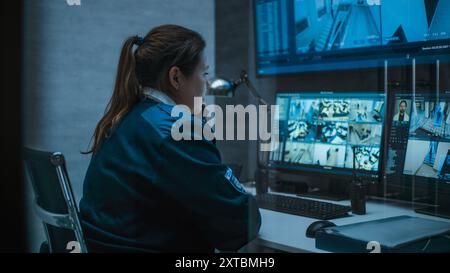 L'operatore di sorveglianza femminile controlla le telecamere di sicurezza con riconoscimento facciale nel centro di monitoraggio tramite computer, parla sul telefono fisso. Riprese CCTV su più monitor e grande schermo digitale. Foto Stock