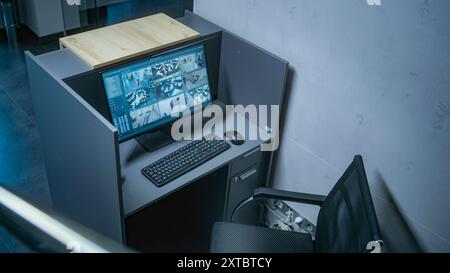 Angolazione elevata del luogo di lavoro per la guardia di sicurezza con un PC all'ingresso dell'ufficio. Monitor del computer che mostra filmati video CCTV dalle telecamere di sorveglianza. Concetto di sicurezza sociale e monitoraggio. Foto Stock