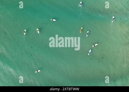 Vista aerea dei surfisti seduti in mare in attesa di un'onda a Point Roadknight sulla Great Ocean Road a Victoria, Australia. Foto Stock