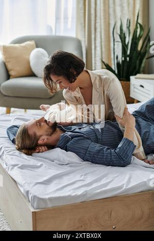 Una coppia amorevole condivide un momento tenero su un letto nella loro casa. Foto Stock