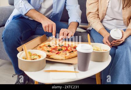 Una giovane coppia gusta il pranzo a casa con pizza, insalata e caffè caldo. Foto Stock