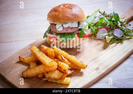 Hamburger di manzo fatto in casa con formaggio blu, patatine fresche fatte in casa e insalata. Foto Stock