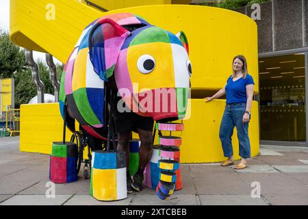 Londra, Regno Unito. 14 agosto 2024. Yvonne Stone, burattinaio e regista, con Elmer, l'elefante patchwork, un burattino gigante, che fa la sua prima apparizione pubblica mentre sfilano fuori dal Southbank Centre, prima di prendere parte al magico adattamento musicale di Tall Stories degli amatissimi libri di Elmer di David McKee. Gli spettacoli si terranno al Lowry di Salford e al Southbank Centre in ottobre. Crediti: Stephen Chung / Alamy Live News Foto Stock