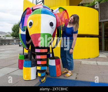 Londra, Regno Unito. 14 agosto 2024. Yvonne Stone, burattinaio e regista, con Elmer, l'elefante patchwork, un burattino gigante, che fa la sua prima apparizione pubblica mentre sfilano fuori dal Southbank Centre, prima di prendere parte al magico adattamento musicale di Tall Stories degli amatissimi libri di Elmer di David McKee. Gli spettacoli si terranno al Lowry di Salford e al Southbank Centre in ottobre. Crediti: Stephen Chung / Alamy Live News Foto Stock