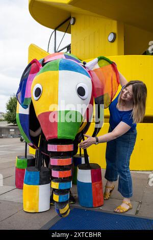 Londra, Regno Unito. 14 agosto 2024. Yvonne Stone, burattinaio e regista, con Elmer, l'elefante patchwork, un burattino gigante, che fa la sua prima apparizione pubblica mentre sfilano fuori dal Southbank Centre, prima di prendere parte al magico adattamento musicale di Tall Stories degli amatissimi libri di Elmer di David McKee. Gli spettacoli si terranno al Lowry di Salford e al Southbank Centre in ottobre. Crediti: Stephen Chung / Alamy Live News Foto Stock