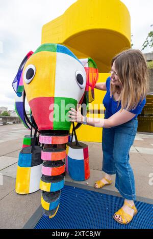 Londra, Regno Unito. 14 agosto 2024. Yvonne Stone, burattinaio e regista, con Elmer, l'elefante patchwork, un burattino gigante, che fa la sua prima apparizione pubblica mentre sfilano fuori dal Southbank Centre, prima di prendere parte al magico adattamento musicale di Tall Stories degli amatissimi libri di Elmer di David McKee. Gli spettacoli si terranno al Lowry di Salford e al Southbank Centre in ottobre. Crediti: Stephen Chung / Alamy Live News Foto Stock