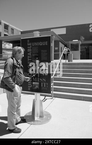 Uomo caucasico di 50 - 60 anni che legge il cartello d'ingresso al cratere Meteor, situato sulla Route 66 all'uscita dell'Interstate 40 vicino a Winslow, Arizona, Stati Uniti. Foto Stock