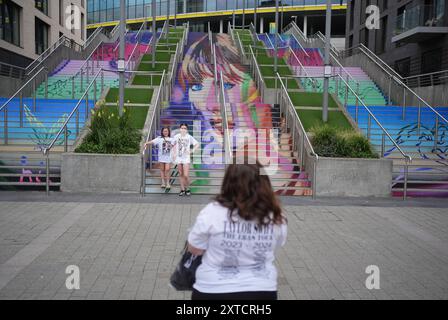 (Da sinistra a destra) Gracie Hiles di otto anni e la sorella di dodici anni Jessica Evans, si pongono come la loro madre (nome non dato) scatta la loro fotografia ai gradini Swiftie e ai murales di Wembley Park, a nord-ovest di Londra, in vista del concerto dell'era Tour di Taylor Swift giovedì. Data foto: Mercoledì 14 agosto 2024. Foto Stock