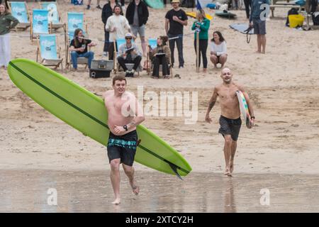 I surfisti che corrono fino al mare per gareggiare nella gara di surf Sand Bandit Showdown al GT Western Great Western Beach di Newquay in Cornovaglia nel Foto Stock