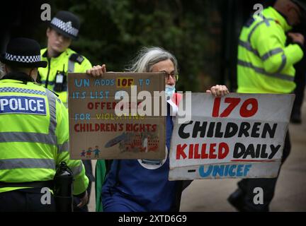 Leicester, Leicestershire, Regno Unito. 14 agosto 2024. Un manifestante tiene dei segnali che illustrano quanto sia stata terribile la guerra di Gaza in Israele per i bambini di Gaza durante la manifestazione. I manifestanti si riuniscono fuori dai cancelli della fabbrica Elbit System a Leicester. Gli operatori sanitari per la Palestina si sono Uniti alla manifestazione molti di loro nei loro scrub per protestare mentre i lavoratori venivano a lavorare presso la compagnia israeliana di armi. I manifestanti protestano contro le armi fabbricate in questa fabbrica che ritengono vengano successivamente utilizzate per opprimere i palestinesi a Gaza e altrove. Il 85% della flotta israeliana di droni è fornita da Elbi Foto Stock