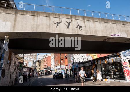 Banksy tre scimmie oscillanti sul ponte ferroviario Brick Lane a Shoreditch Londra, 13 agosto 2024, parte della sua collezione di zoo Foto Stock