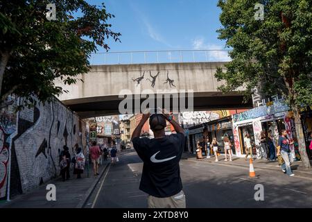 Banksy tre scimmie oscillanti sul ponte ferroviario Brick Lane a Shoreditch Londra, 13 agosto 2024, parte della sua collezione di zoo Foto Stock