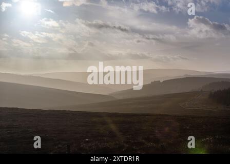 Tramonto sulla campagna nebbiosa di Kielder, Northumberland, catturando il tranquillo paesaggio sotto un cielo pieno di nuvole Foto Stock