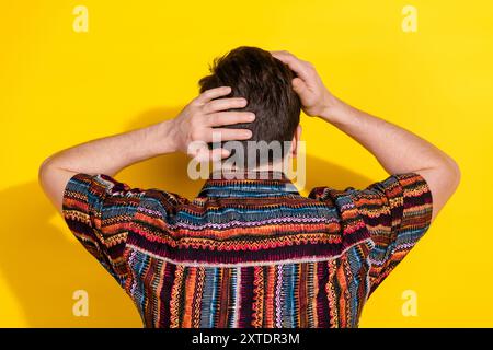 Ritratto posteriore di un giovane uomo simpatico, camicia da parrucchiere isolata su sfondo di colore giallo Foto Stock