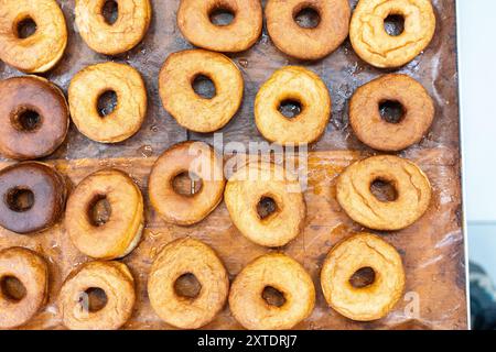 Produzione di ciambelle. Le ciambelle sono fritte, smaltate e disposte su scaffali di una panetteria di ciambelle. Foto di alta qualità Foto Stock