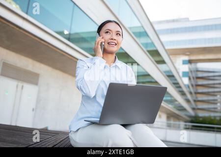 Giovane professionista impegnato nel lavoro mentre parla al telefono all'aperto Foto Stock