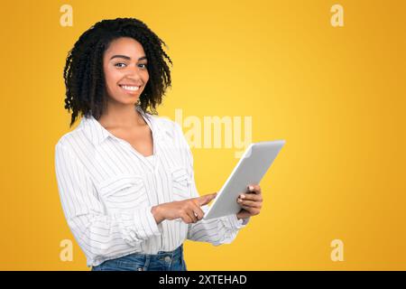 Sorridente ragazza nera in piedi con tablet in studio Foto Stock