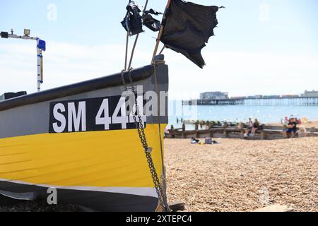 Barca da pesca sulla spiaggia di Worthing, con il molo oltre, nel West Sussex, Regno Unito Foto Stock