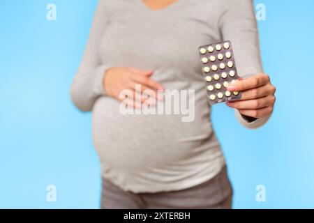 Irriconoscibile incinta ragazza mostra pillole Blister in piedi in Studio Foto Stock