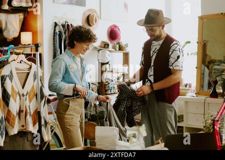 Smistamento di capi nel negozio di abbigliamento Vintage con ripiani Foto Stock