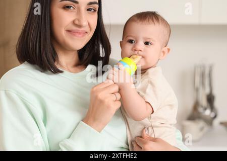 Madre che dà al suo piccolo stuzzichino con il cibo in cucina, primo piano Foto Stock