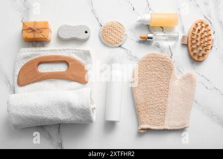 Composizione con strumento di massaggio corpo guasha in legno e prodotti da bagno su fondo in marmo Foto Stock