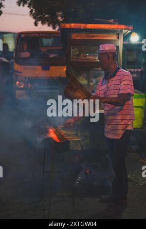 Balikpapan, Indonesia - 15 giugno 2024. è un venditore di cibo di strada che grigia alcuni satay per i suoi clienti. Foto Stock