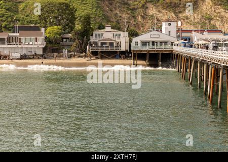 Malibu, California, USA - 9 settembre 2023: La luce del sole pomeridiano brilla sullo storico Malibu Pier mentre le onde si infrangono su Carbon Beach. Foto Stock