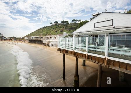 Malibu, California, USA - 9 settembre 2023: La luce del sole pomeridiano brilla sullo storico Malibu Pier mentre le onde si infrangono su Carbon Beach. Foto Stock