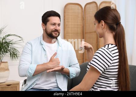 Uomo e donna che usano il linguaggio dei segni per comunicare a casa Foto Stock