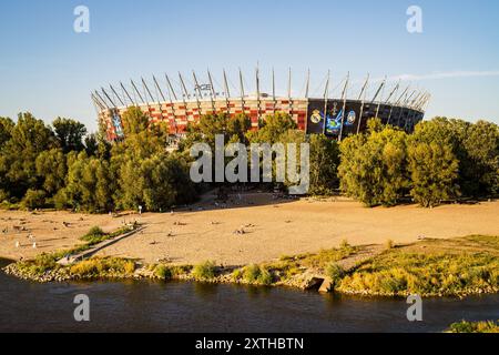 Il PGE Narodowy viene immerso nella luce della prima sera prima della partita. I tifosi dei vincitori della Champions League spagnola, del Real Madrid e della Coppa UEFA italiana, l'Atalanta, si sono riuniti in piazza Kahla a Varsavia, accanto al fiume Vistola, per il festival dei tifosi della Supercoppa UEFA. In previsione della partita di quella sera, i visitatori fanno la fila per scattare foto con il trofeo e partecipare a diverse partite e attività legate al calcio, prima di recarsi allo stadio per la partita. La Supercoppa UEFA si svolge al PGE Narodowy di Varsavia il 14 agosto 2024 ed è contesa dai vincitori dei campioni Leagu Foto Stock