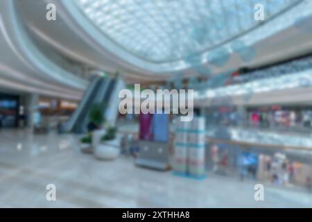 Una vista sfocata di un centro commerciale a Shenzhen, in Cina. L'immagine presenta una scala mobile, più piani e un soffitto di vetro con illuminazione bokeh. Foto Stock