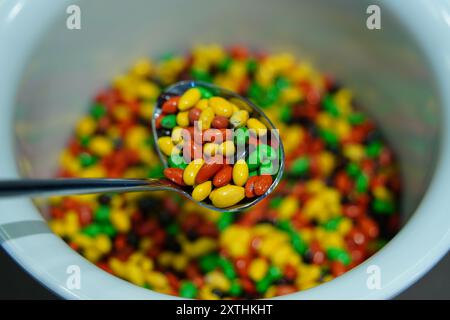 Colorati semi di girasole ricoperti di cioccolato in un recipiente di plastica Foto Stock