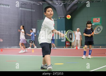 (240815) -- PECHINO, 15 agosto 2024 (Xinhua) -- bambini gli studenti partecipano a un campo estivo di tennis in un club di tennis a Pechino, Cina, 14 agosto 2024 la Cina ha recentemente sperimentato un aumento dell'entusiasmo per il tennis, come evidenziato da un notevole aumento della domanda di corsi di formazione e prenotazioni di campi in varie città. Questo picco può essere attribuito alla storica vittoria del tennista cinese Zheng Qinwen, che ha conquistato la prima medaglia d'oro del tennis olimpico cinese alle Olimpiadi di Parigi. Vale la pena ricordare che non solo più adulti hanno praticato il tennis come attività ricreativa, ma anche un Foto Stock