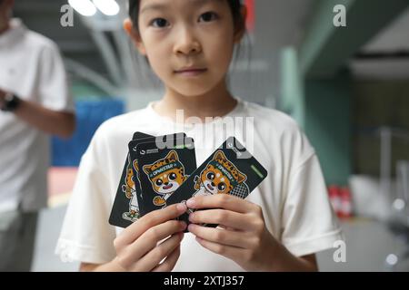 (240815) -- PECHINO, 15 agosto 2024 (Xinhua) -- un bambino mostra le carte premio dopo aver partecipato a un campo estivo di tennis in un club di tennis a Pechino, Cina, 14 agosto 2024 la Cina ha recentemente sperimentato un aumento dell'entusiasmo per il tennis, come dimostra un notevole aumento della domanda di corsi di formazione e prenotazioni di campi in varie città. Questo picco può essere attribuito alla storica vittoria del tennista cinese Zheng Qinwen, che ha conquistato la prima medaglia d'oro del tennis olimpico cinese alle Olimpiadi di Parigi. Vale la pena ricordare che non solo più adulti hanno iniziato a giocare a tennis come ricreazione Foto Stock