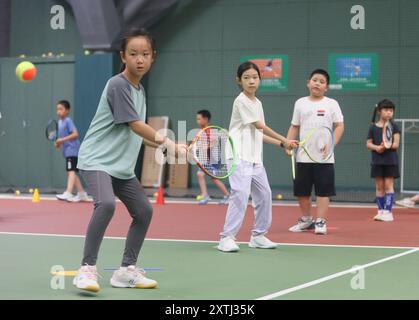 (240815) -- PECHINO, 15 agosto 2024 (Xinhua) -- bambini gli studenti partecipano a un campo estivo di tennis in un club di tennis a Pechino, Cina, 14 agosto 2024 la Cina ha recentemente sperimentato un aumento dell'entusiasmo per il tennis, come evidenziato da un notevole aumento della domanda di corsi di formazione e prenotazioni di campi in varie città. Questo picco può essere attribuito alla storica vittoria del tennista cinese Zheng Qinwen, che ha conquistato la prima medaglia d'oro del tennis olimpico cinese alle Olimpiadi di Parigi. Vale la pena ricordare che non solo più adulti hanno praticato il tennis come attività ricreativa, ma anche un Foto Stock