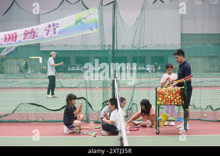 (240815) -- PECHINO, 15 agosto 2024 (Xinhua) -- bambini gli studenti partecipano a un campo estivo di tennis in un club di tennis a Pechino, Cina, 14 agosto 2024 la Cina ha recentemente sperimentato un aumento dell'entusiasmo per il tennis, come evidenziato da un notevole aumento della domanda di corsi di formazione e prenotazioni di campi in varie città. Questo picco può essere attribuito alla storica vittoria del tennista cinese Zheng Qinwen, che ha conquistato la prima medaglia d'oro del tennis olimpico cinese alle Olimpiadi di Parigi. Vale la pena ricordare che non solo più adulti hanno praticato il tennis come attività ricreativa, ma anche un Foto Stock