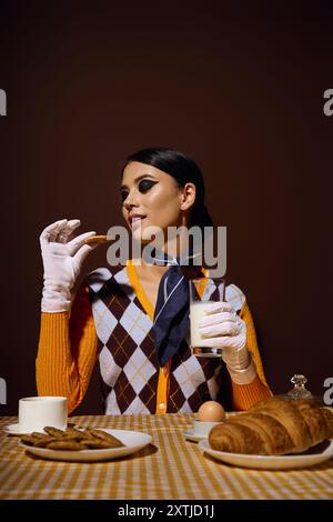 Una giovane donna, vestita con abiti alla moda, gode di una piacevole colazione. Foto Stock