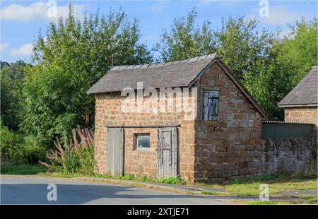 Beeston, Cheshire West e Chester, Regno Unito - 14 agosto 2024 - vecchio fienile in pietra con porte a fienile sul lato della strada Foto Stock