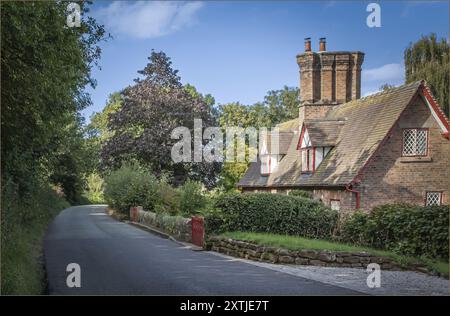 Beeston, Cheshire West e Chester, UK - 14 agosto 2024 - cottage tradizionali con alti camini e cancelli dipinti di rosso Foto Stock