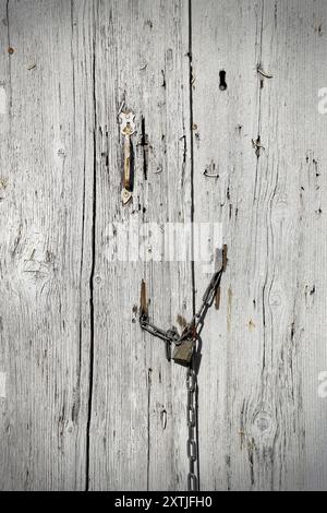 Molto vecchia porta di legno con maniglia e lucchetto appeso sulla catena Foto Stock