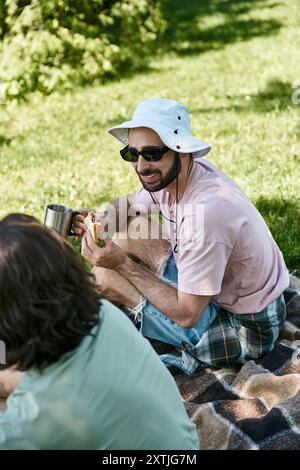 Una giovane coppia gay si diverte a fare un picnic estivo nella natura selvaggia. Foto Stock