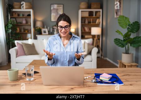 Videochiamata da donna d'affari. Giovane donna di successo che lavora a casa, parla con i colleghi con la webcam del laptop, ha una riunione virtuale del personale, givi Foto Stock